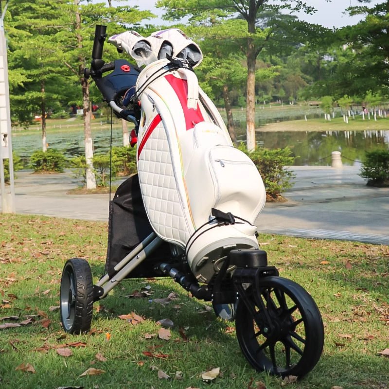 Silver-frame push cart on the fairway carrying a white quilted cart bag